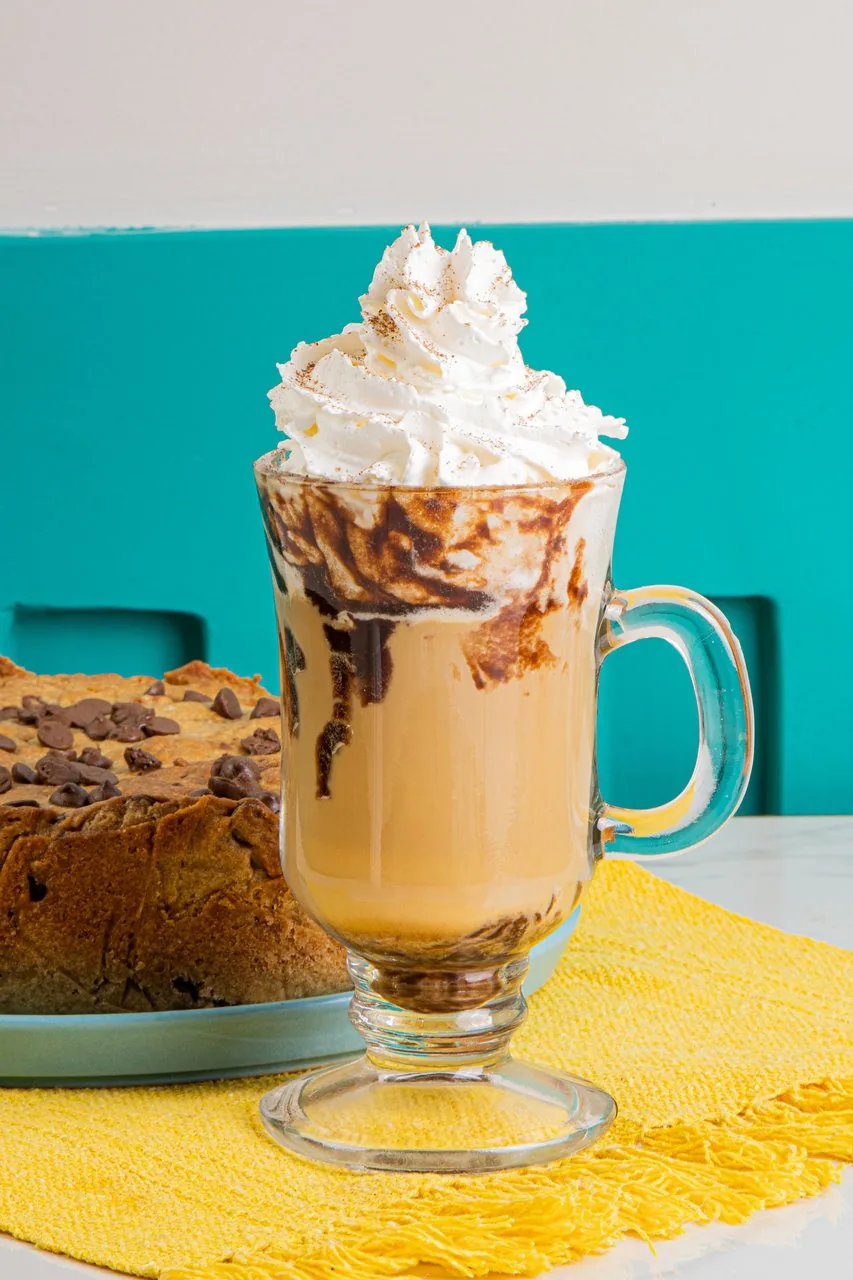 Café com chantilly ao lado da torta cookie do Divino